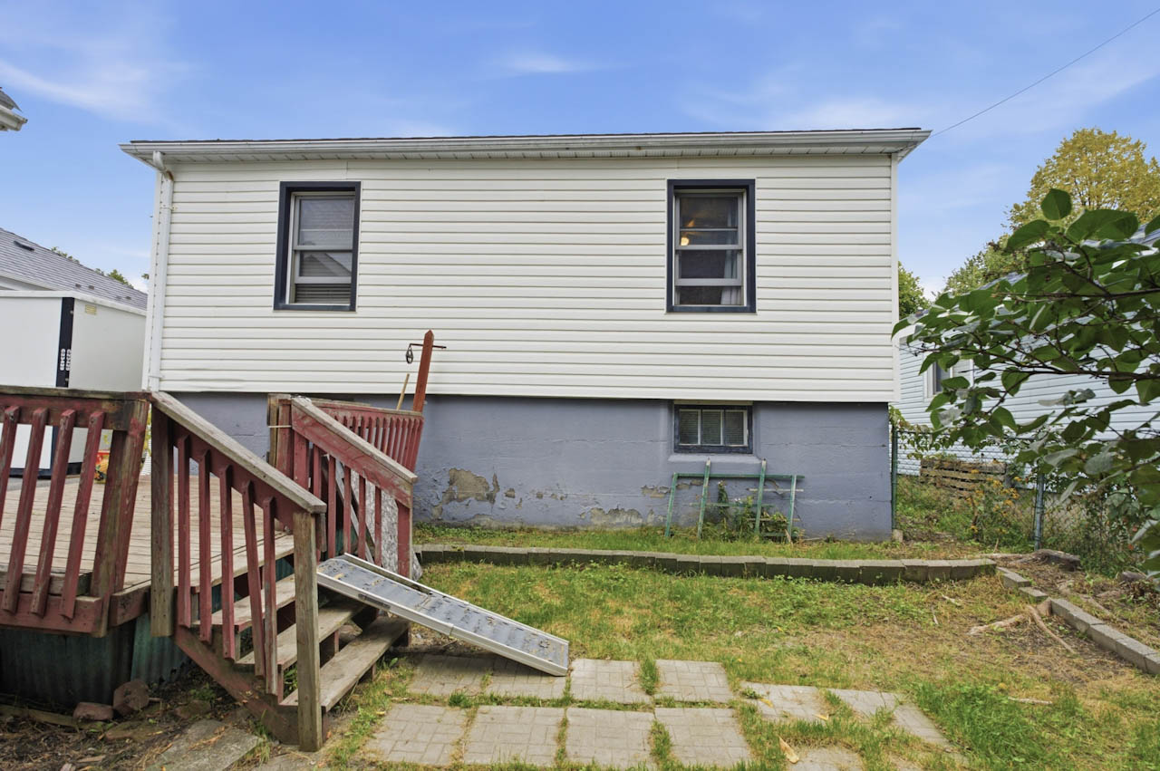Rear of the home with a back deck, stairs, and the yard