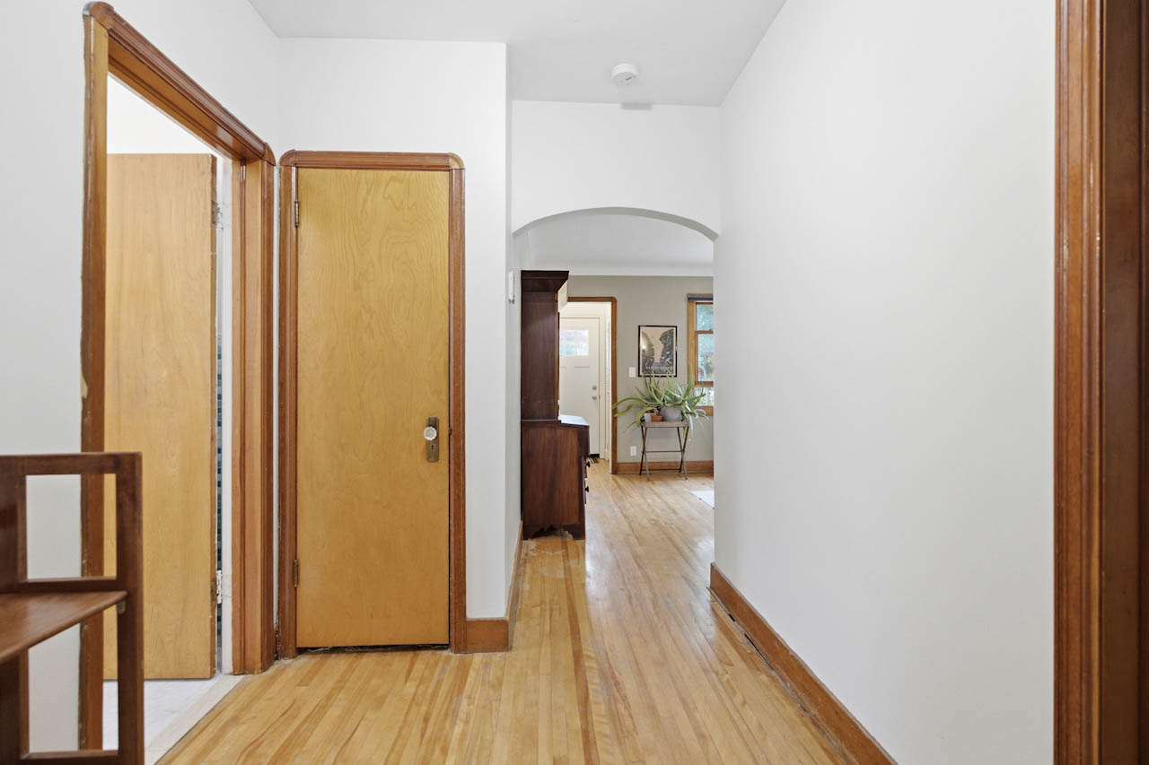 Hall with wood doors, trim, and an arched opening into the living room