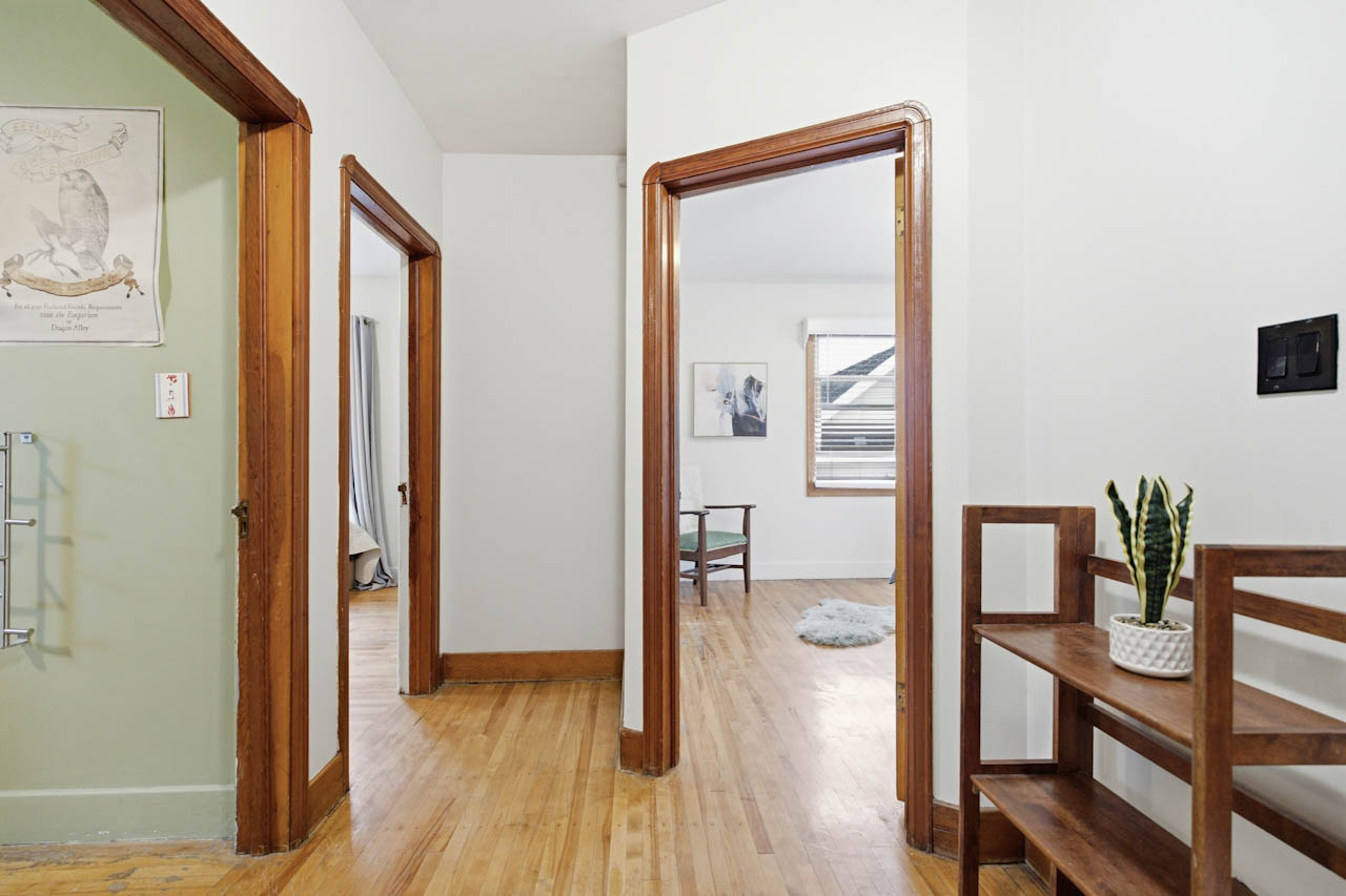 Hallway with original hardwood and stained wood door casings leading to the bedrooms