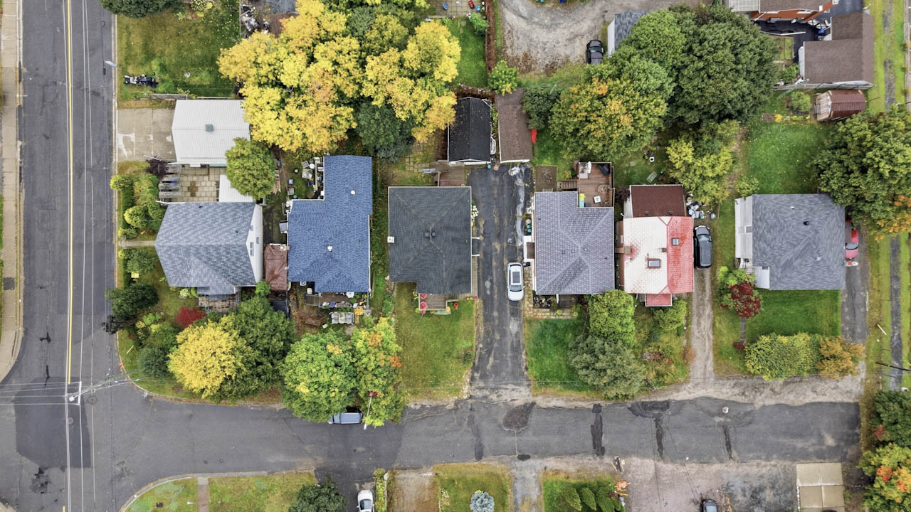 Overhead drone view of the home and neighbouring lots on a tree-lined street