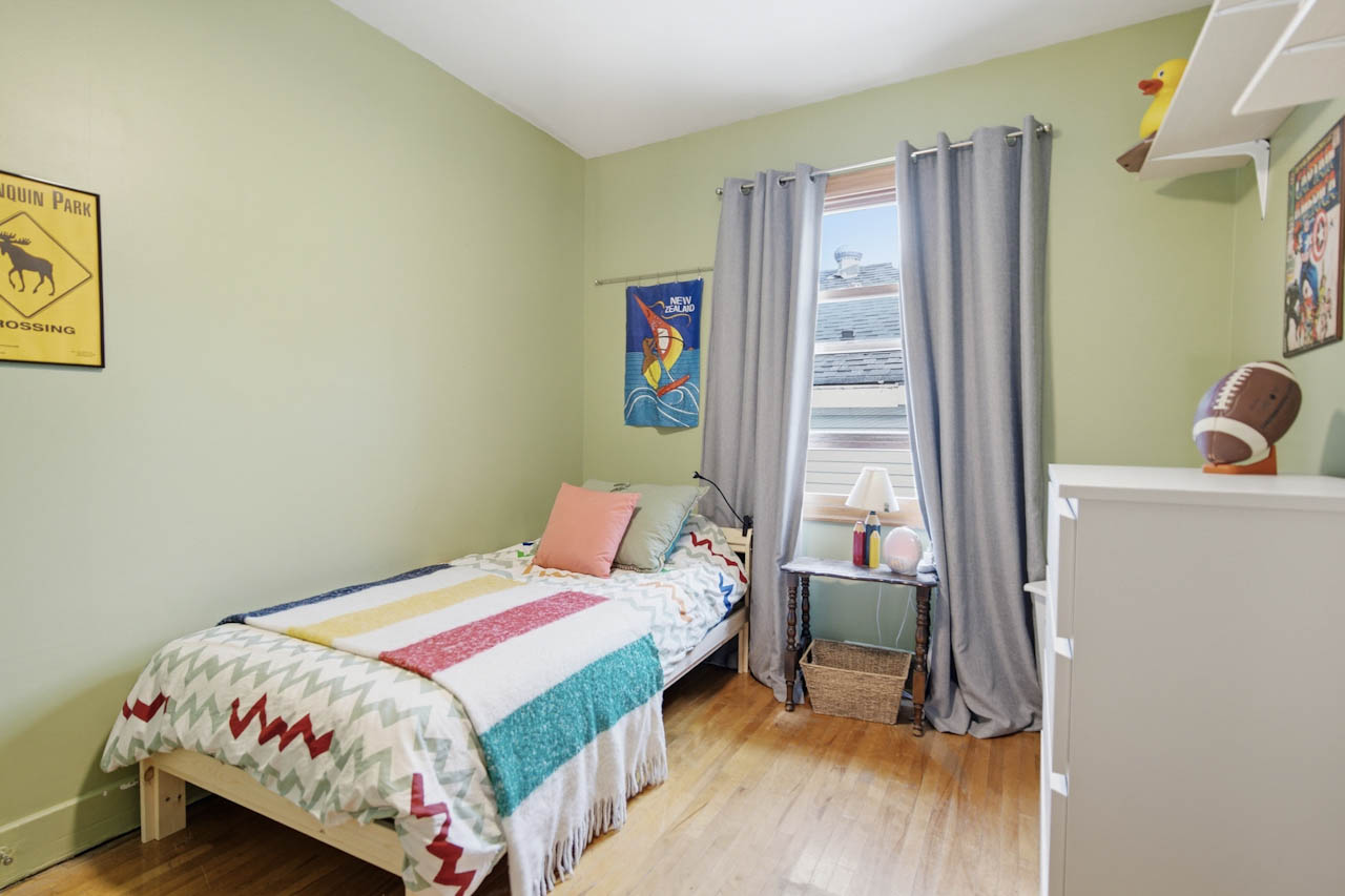 Green-walled bedroom with hardwood floor and a single bed