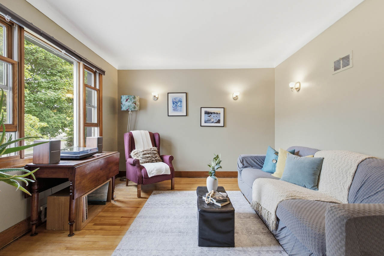 Living room with a large wood-framed window looking onto green trees